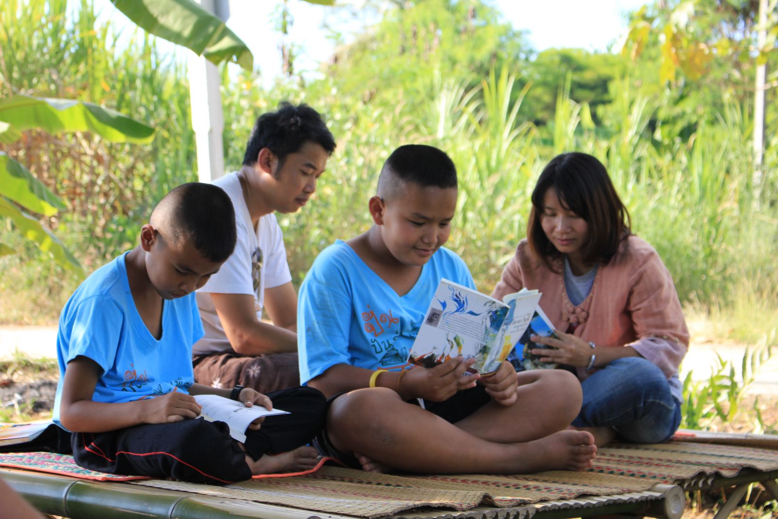 น้องฟอต น้องเอฟ และพี่ๆกลุ่มสถาบันไทเลย นั่งอ่านหนังสือใต้ต้นไม้